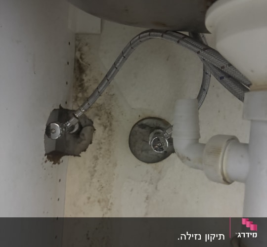 צנרת מתחת לכיור עם סימני רטיבות ועובש